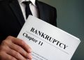 Man holds Bankruptcy Chapter 11 agreement documents.