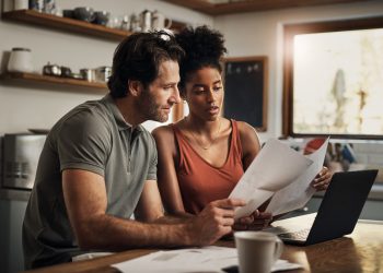 Cropped shot of an affectionate young couple going through paperwork while doing their budget at home