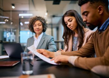 African American woman and her husband going through documents during a meeting with financial advisor.